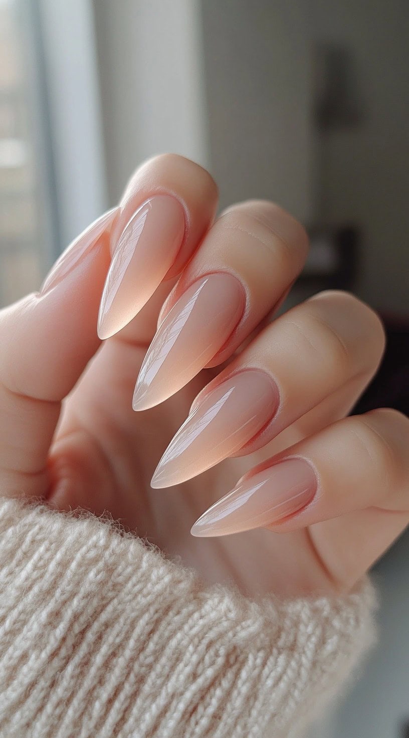 Translucent nude almond-shaped nails with a high-gloss finish, creating a soft, natural look.