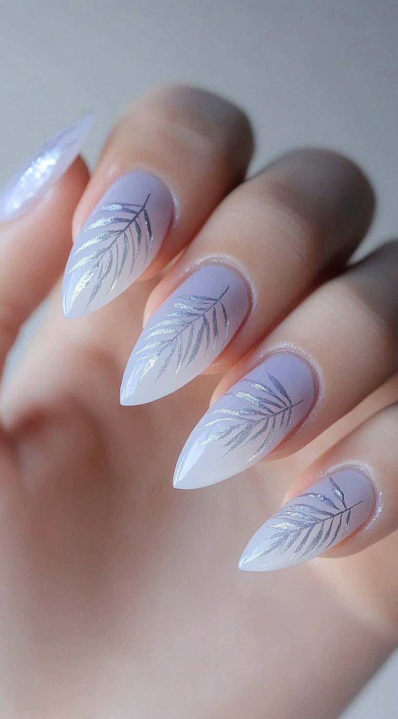Almond-shaped nails with a light lavender base and silver leaf pattern.