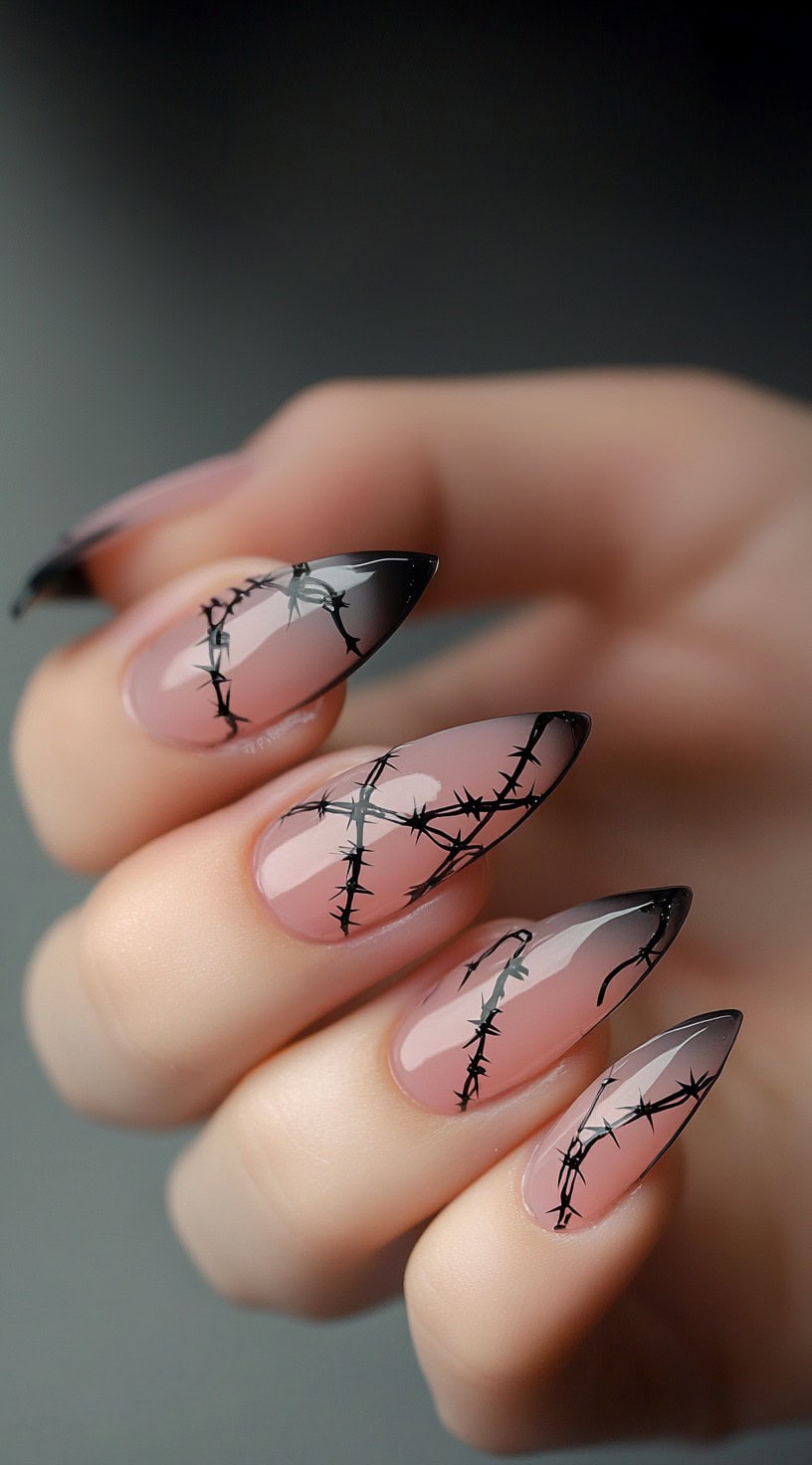 Almond-shaped nails with a pink ombre base and black barbed wire design.