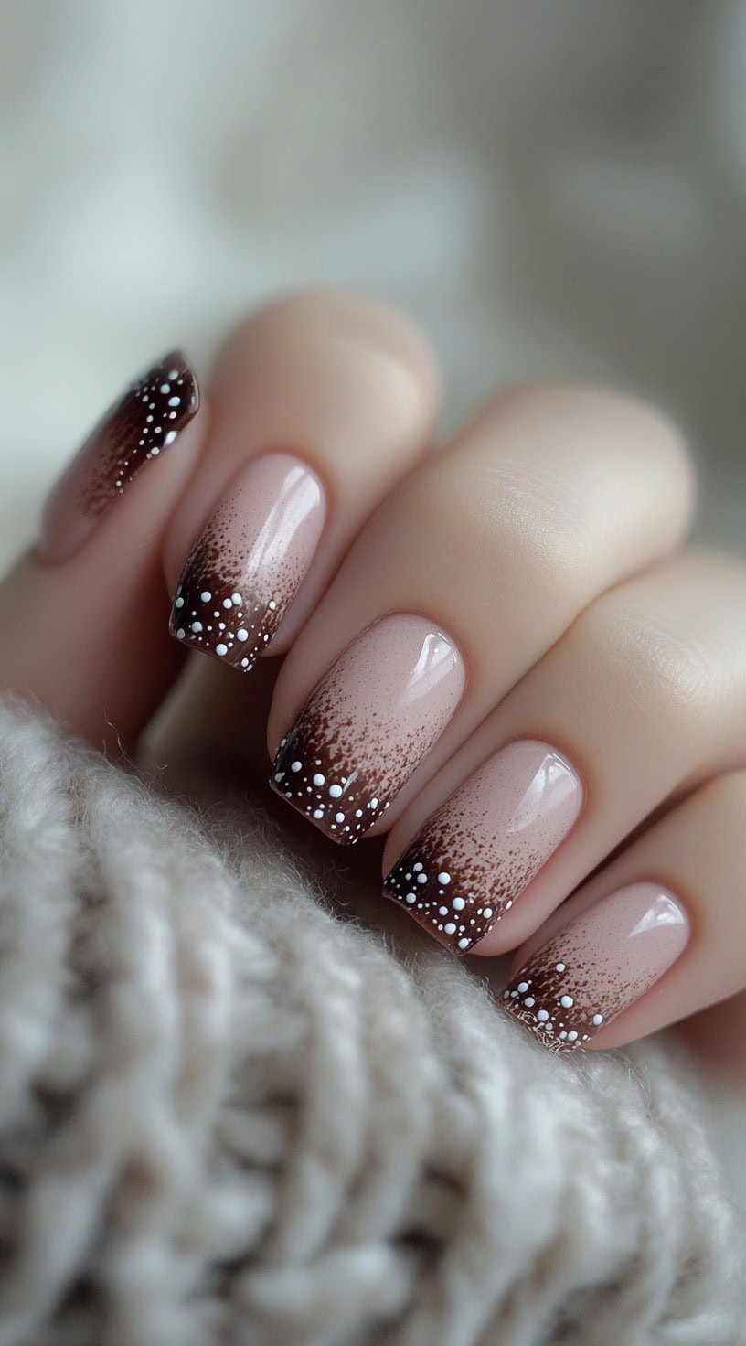 Square nails feature a soft brown to pink ombre with white dot accents resembling falling snow.