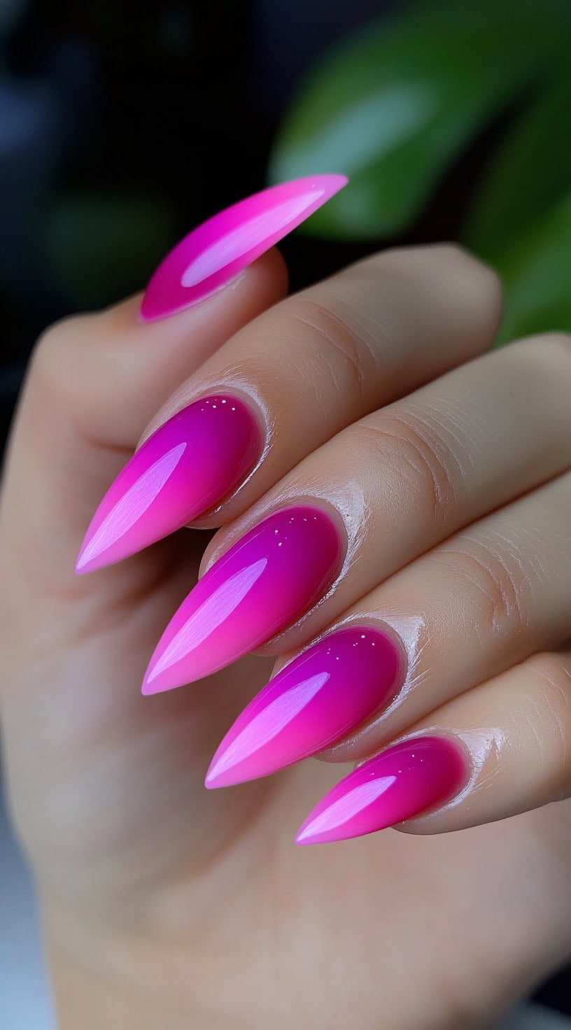 Stiletto-shaped nails featuring a vivid hot pink to purple ombre with a glassy high-shine finish.