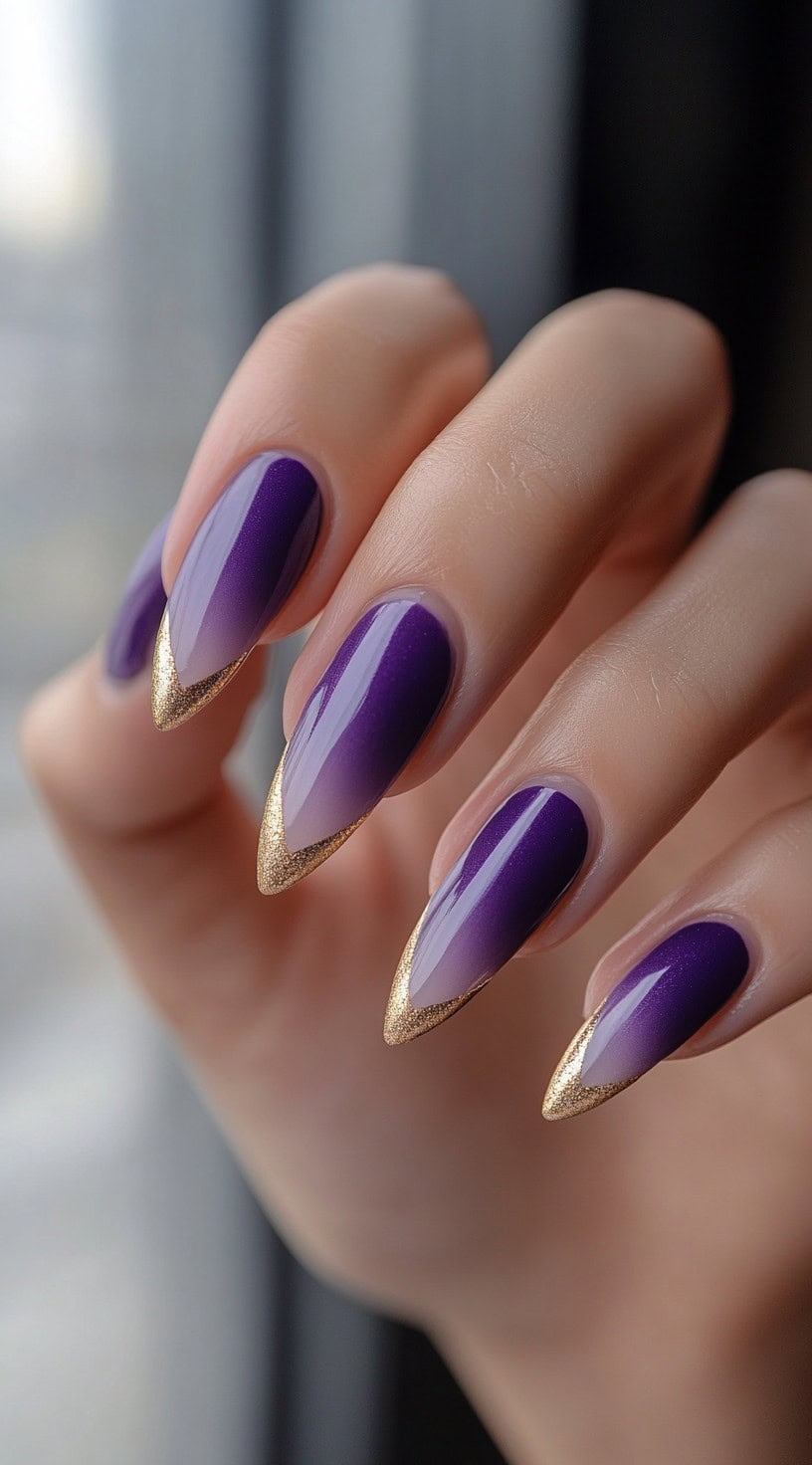 Pointed stiletto nails featuring a soft purple gradient with metallic gold foil accents on the tips.