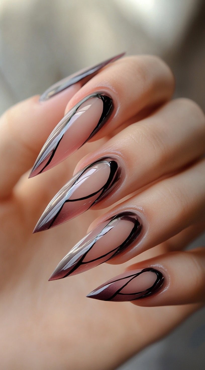 Stiletto nails display a pink to brown gradient accented with sharp black abstract line work over the tips.