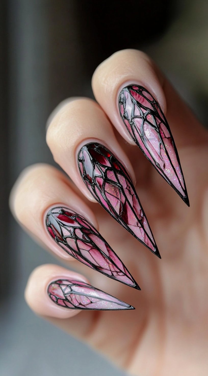 Long stiletto nails with transparent pink polish and black vein-like web designs.
