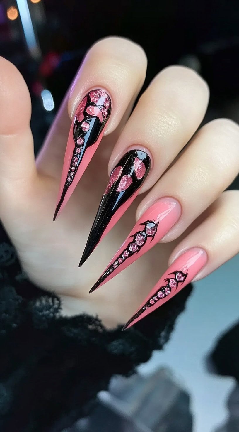 Very long stiletto pink nails with shiny black drips and embedded pink rhinestones.